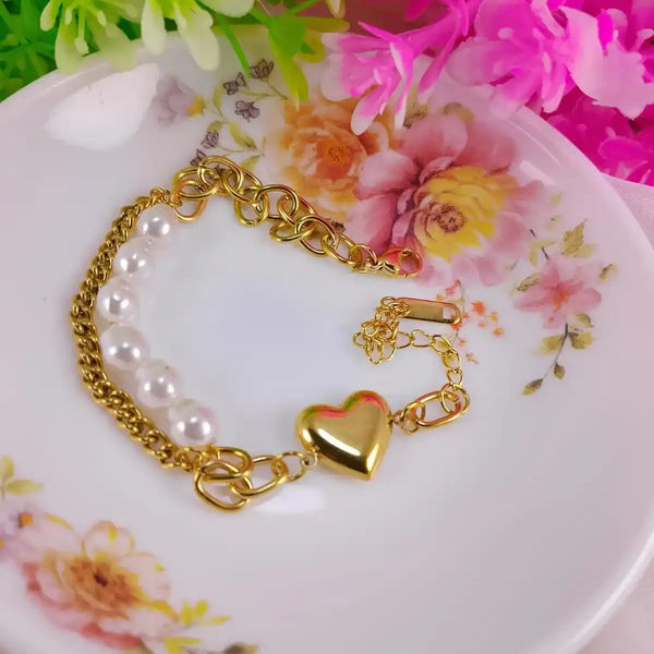 Gold bracelet with heart charm on a floral plate