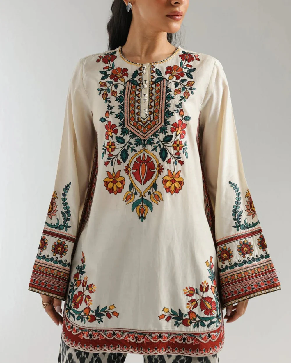 Woman wearing a traditional embroidered outfit with a plain background